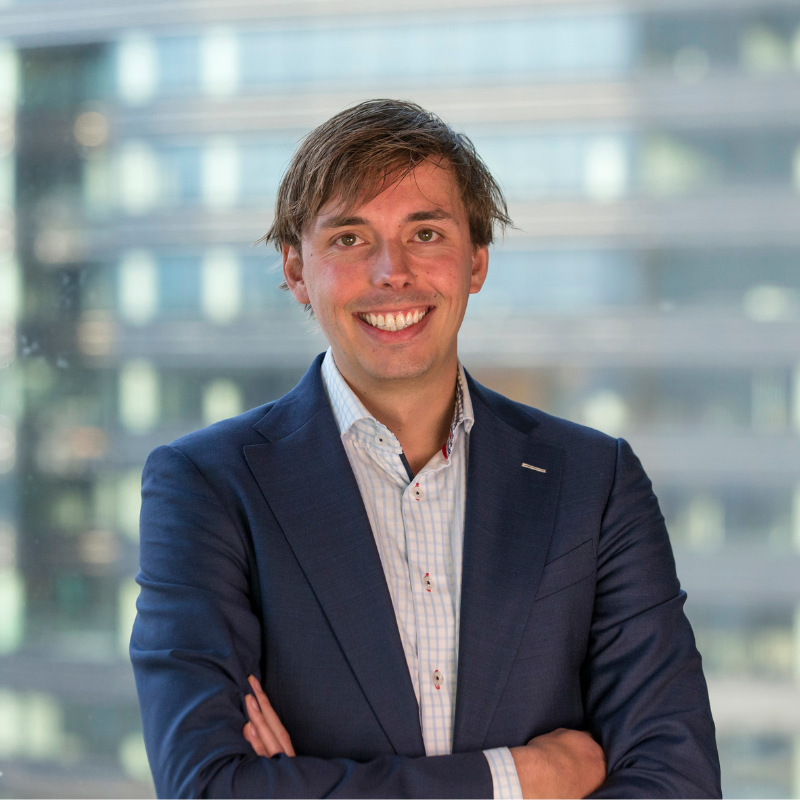 Professional headshot of Kevin Klein, a smiling man with brown hair wearing a navy blazer over a checked shirt, against a blurred office background.