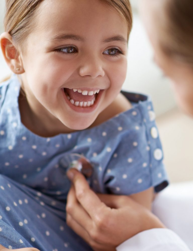 Happy child, girl and stethoscope of doctor for medical consulting, healthy lungs and listening to heartbeat. Face of laughing kid, pediatrician and chest assessment for healthcare analysis in clinic.